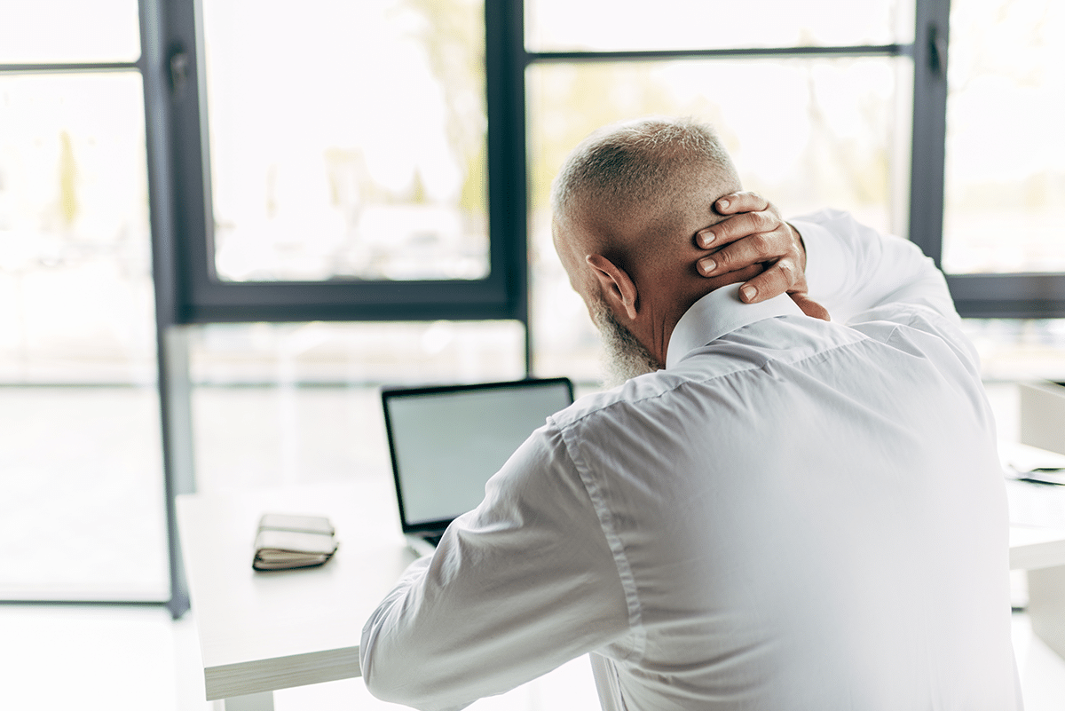 man holding neck at computer